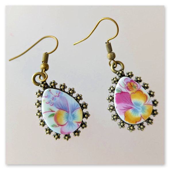 Das Stiefmütterchen-Motiv ist in einer tropfenförmigen antik anmutenden bronzefarbenen Fassung aus einer Metalllegierung eingelassen. 