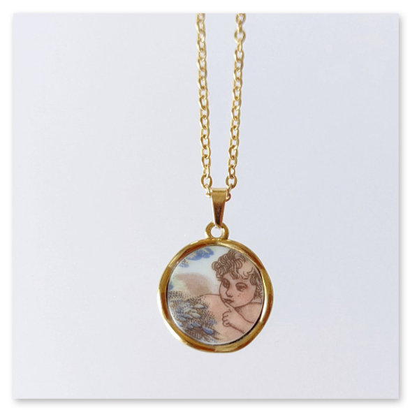 Das aus einem Porzellanteller ausgeschnittene Motiv, ein geflügelter Engel, wurde sorgfältig geschliffen und in eine kleine vergoldete Edelstahlfassung eingepasst.