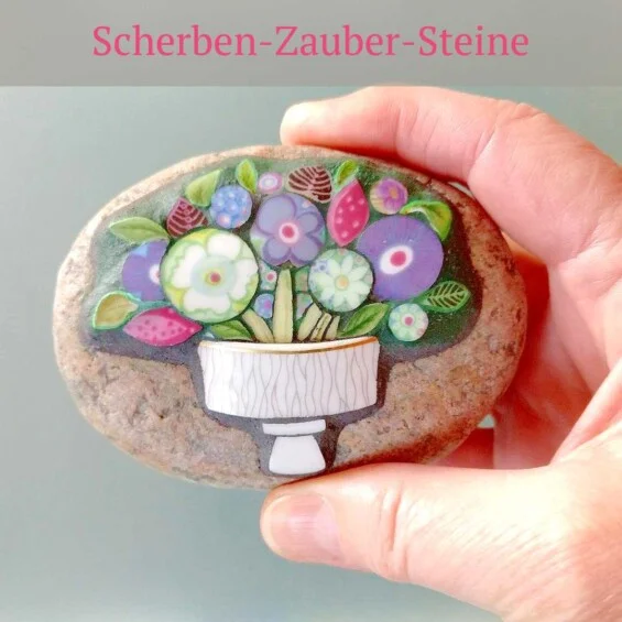 Jeder ScherbenZauberStein ist ein Unikat mit einem kleinen handgefertigten Mosaik. Die Mosaiken werden auf glatten flachen Steinen gelegt. Sie entstehen aus  exakt zugeschnittenen Porzellanscherben in Kombination mit Farbglas.